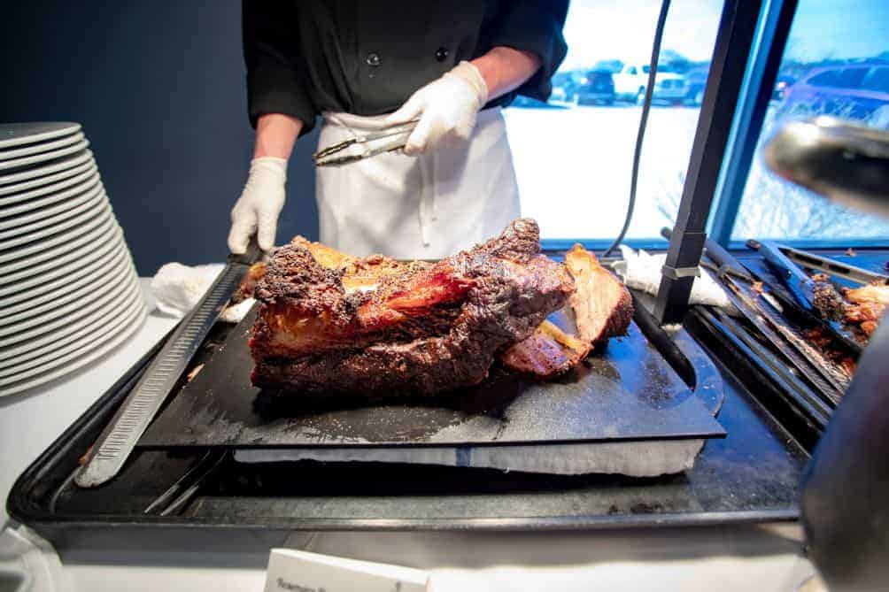 Chef carving and serving a large roast at a catered event