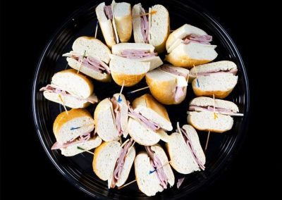 Assorted mini sandwiches on a black platter for gatherings.