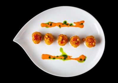 Gourmet appetizer with colorful sauces and crispy bites on a white plate.