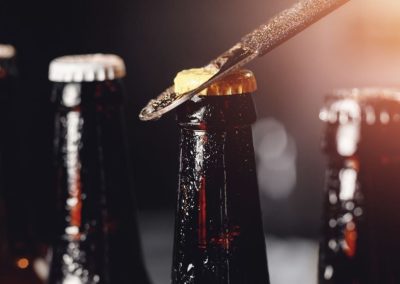 Close-up of beer bottles with lemon slice on top, dark background, warm lighting.