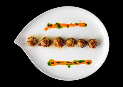 Gourmet appetizer with sauce garnishes on white plate.
