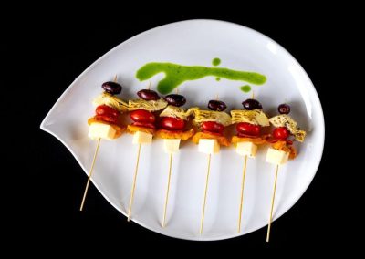 Fresh Caprese skewers with cherry tomatoes, mozzarella, basil, and balsamic glaze on a white plate.