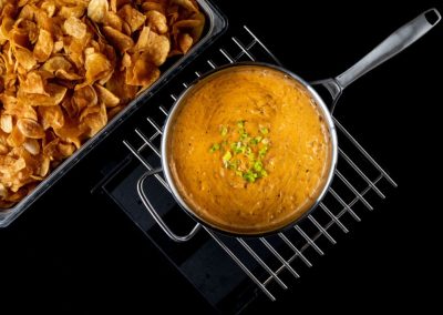 Close-up of lentil soup garnished with green herbs and crispy chips on the side.