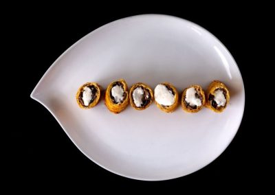 Assorted sushi rolls with rice and seaweed on a white dish against black background.