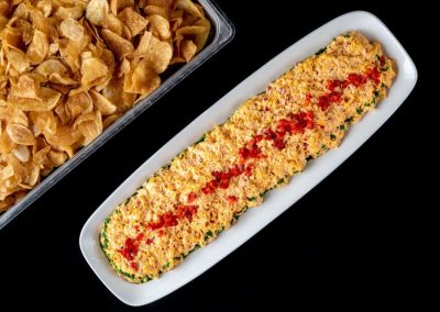 Crispy breaded zucchini boat with red pepper topping on white dish.