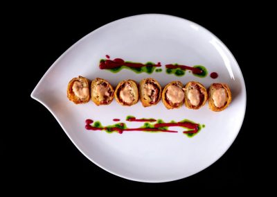 Delicious sushi roll with colorful sauces on a white plate.