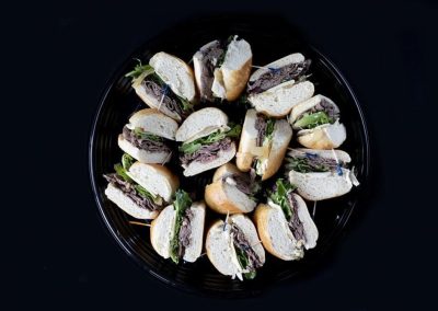 Assorted sandwiches with beef, lettuce, and bread on a black plate.
