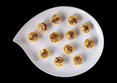 Gourmet pasta with meat filling served on a white leaf-shaped plate.