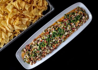 Colorful ceviche dish with herbs and vegetables on a white plate.