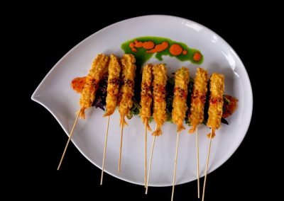 Chicken skewers with sauce on a white plate, close-up view.