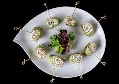 Vegetable roll appetizers with fresh greens on a white plate.