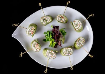Vegetable roll appetizers with fresh greens on a white plate.