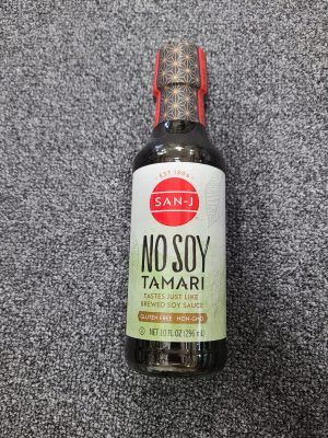 San J No Soy Tamari gluten-free soy sauce bottle on gray carpet.