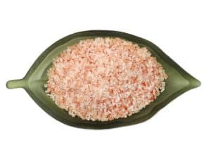 Himalayan pink salt crystals on a green leaf-shaped dish for healthy cooking.