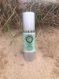 Healthy Roots CBD Cream bottle on sandy beach with grass in background.