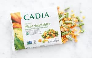 Healthy Roots organic mixed vegetables in a bag with scattered pieces on a white surface.