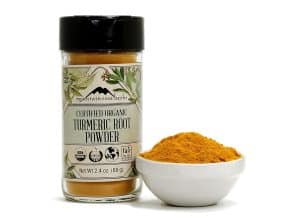 Certified organic turmeric root powder in a jar with a bowl of powder.