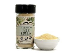 Organic garlic granules in a jar with a bowl of powder.