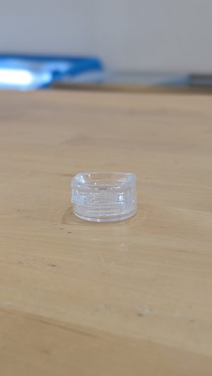 Mini clear lip balm container on wooden surface for Healthy Roots products.