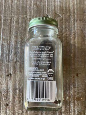 Vanilla beans in a glass jar on wooden surface for healthy cooking.