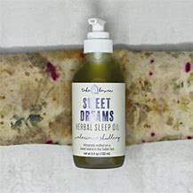 Herbal sleep oil bottle on rustic surface with pump dispenser.
