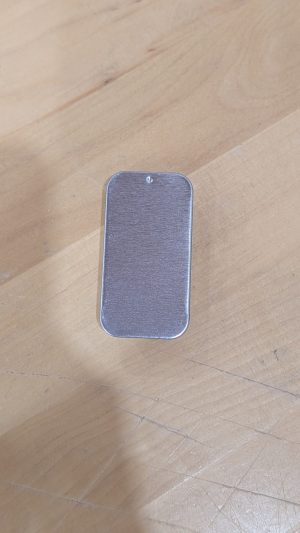 Small metallic salve tin on wooden surface for natural skincare products.
