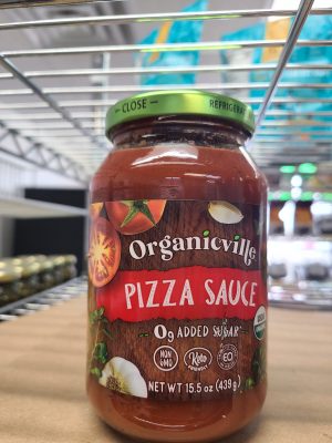 Organicville pizza sauce jar with fresh ingredients label on a store shelf.