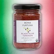 Healthy Roots Black Olive Tapenade in glass jar on green and pink background.