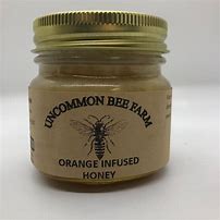 Jar of orange infused honey from Uncommon Bee Farm with gold lid.