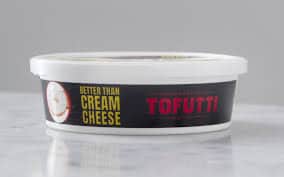 Tofutti vegan cream cheese container on a white surface.