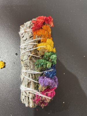 Colorful sage and flower smudge bundle for cleansing rituals.