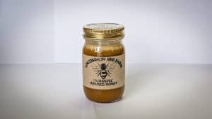 Jar of turmeric infused honey from Uncommon Bee Farm on a white background.