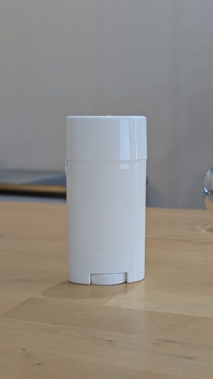 White deodorant container on wooden surface, minimalistic design.