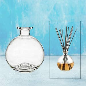 Round glass diffuser bottle with reed sticks for aromatherapy.