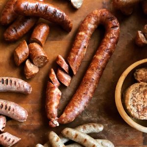 Freshly cooked andouille sausage with slices on a wooden surface.
