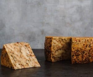Close-up of aged artisanal cheese blocks on dark surface.
