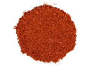 Ancho chili powder in a round pile, vibrant red-orange color.
