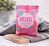Vegan organic raspberry and blackcurrant gummies in pink packaging on wooden surface.