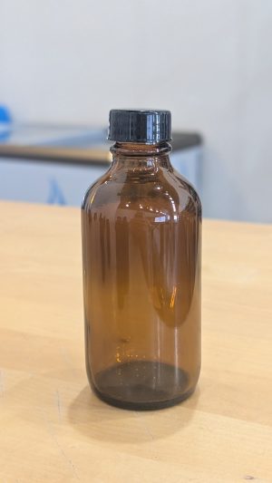 Amber glass bottle with black plastic cap for cosmetic or essential oil storage.