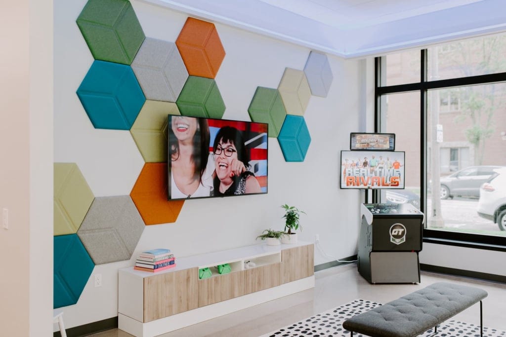 Contemporary office lounge with colorful hexagon wall art and TV.