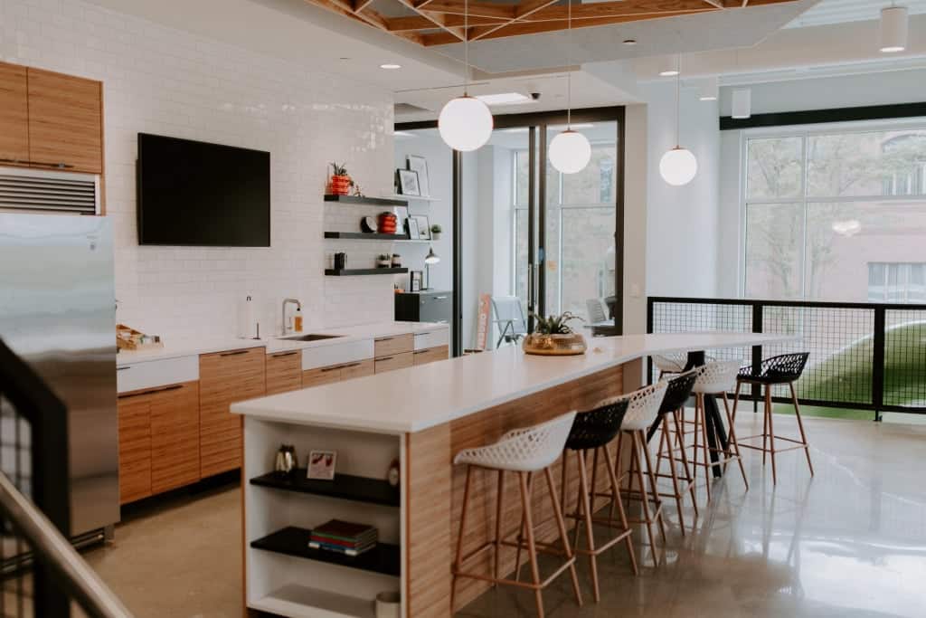 Contemporary kitchen with island, bar stools, and large windows in Michigan home.