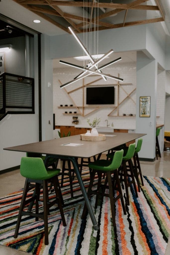 Contemporary dining room with green chairs and geometric wall decor.