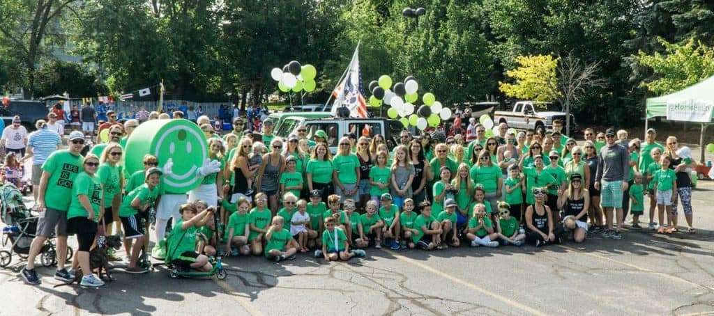 Happy outdoor community event with families and volunteers, promoting local real estate and housing