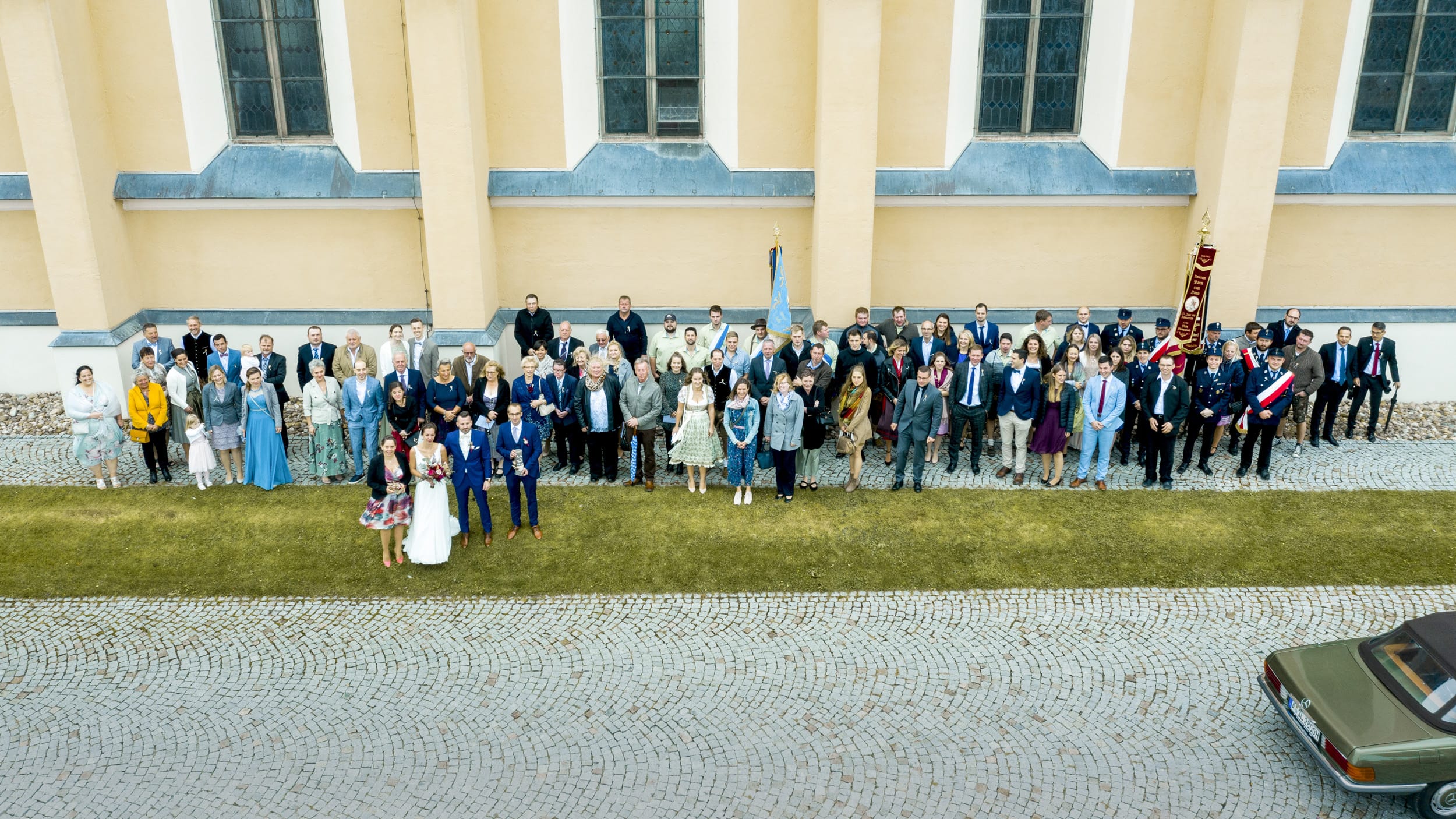 Gruppenbild der Hochzeitsgesellschaft mit Drohne vor der Kirche Aindling aufgenommen