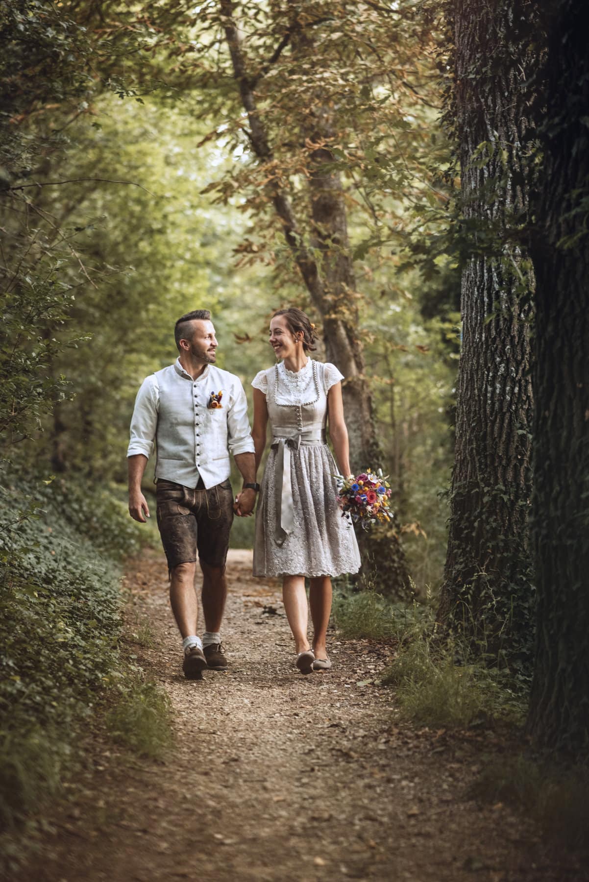 Hochzeitspaar beim Hochzeitshooting auf einem Weg im Wald in Thierhaupten laufen