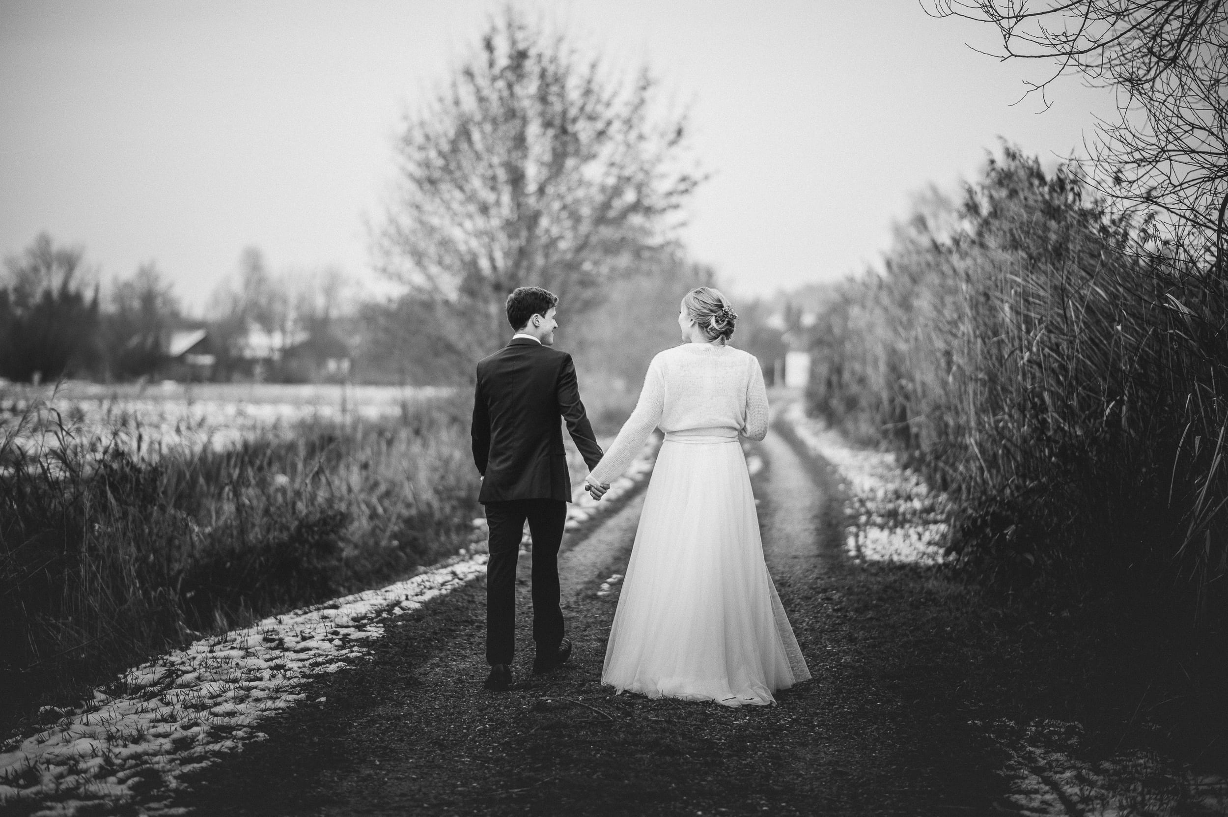 Brautpaar reicht sich die Hand und geht ein paar Schritte beim Hochzeitsshooting am Klosterweiher in Thierhaupten