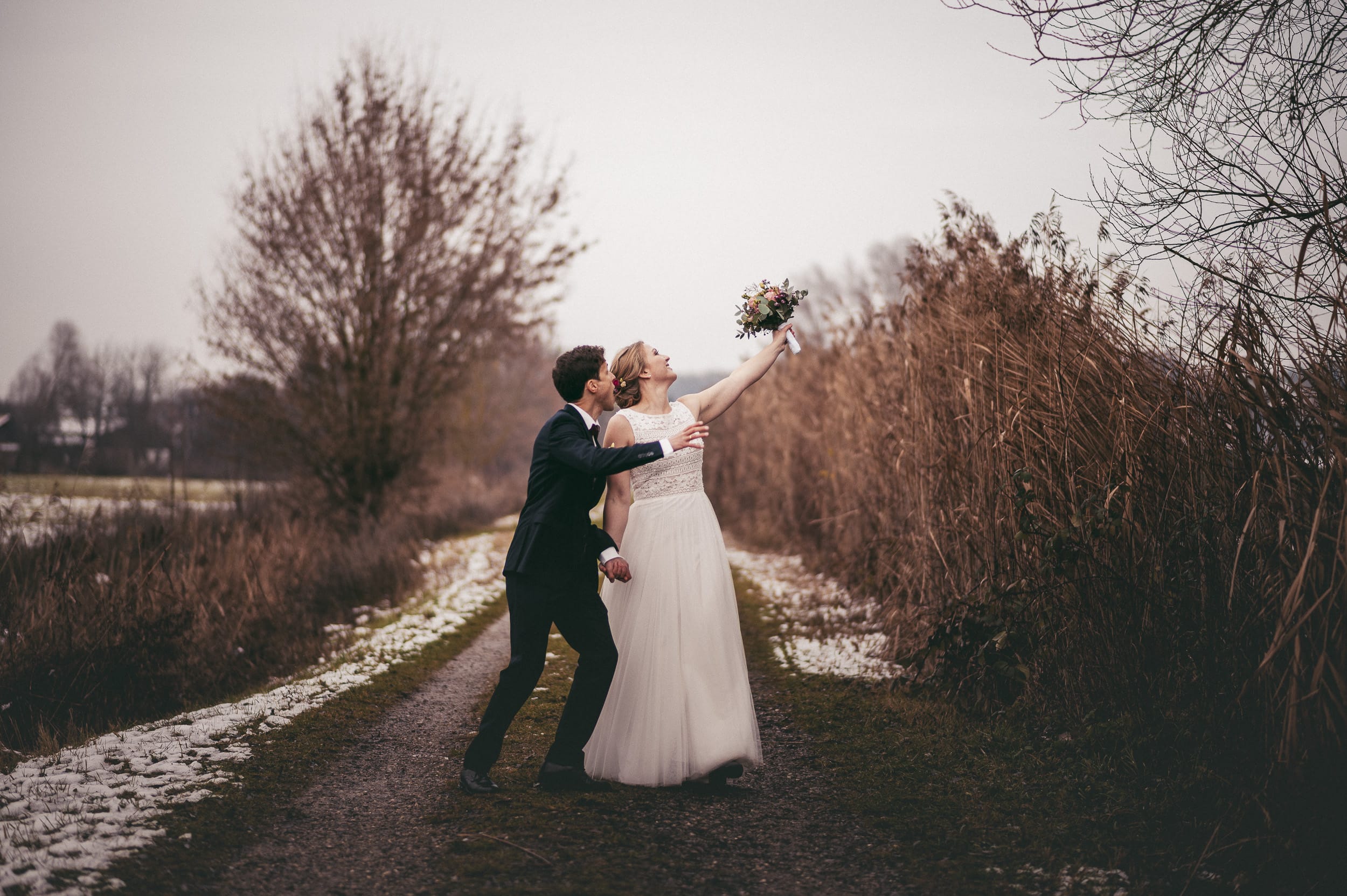 Bräutigam versucht seiner Braut beim Hochzeitsshooting den Braustrauß zu klauen