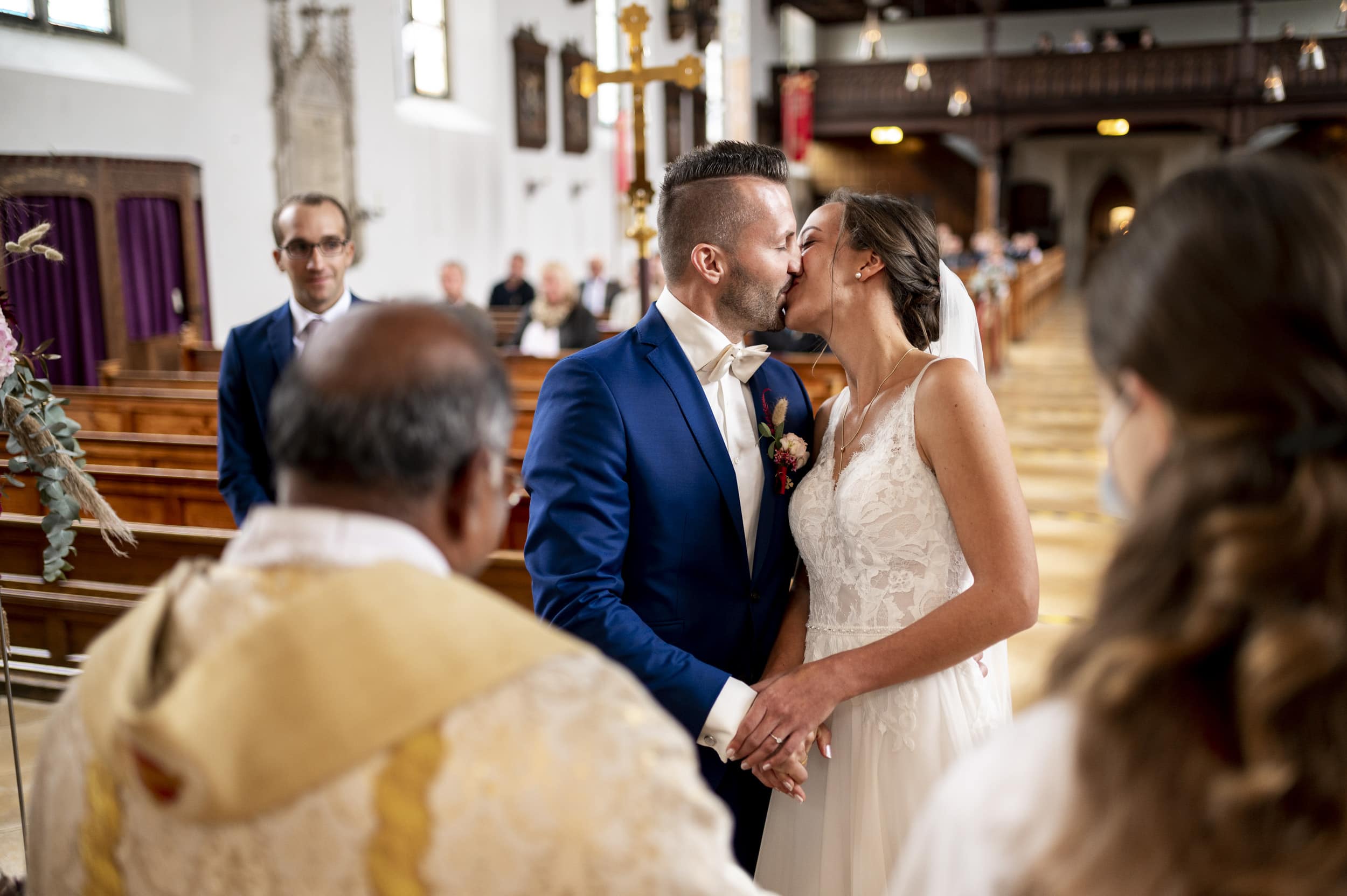 Hochzeitspaar küsst sich glücklich nach JA-Wort und Ringe Anstecken in der Kirche in Aindling