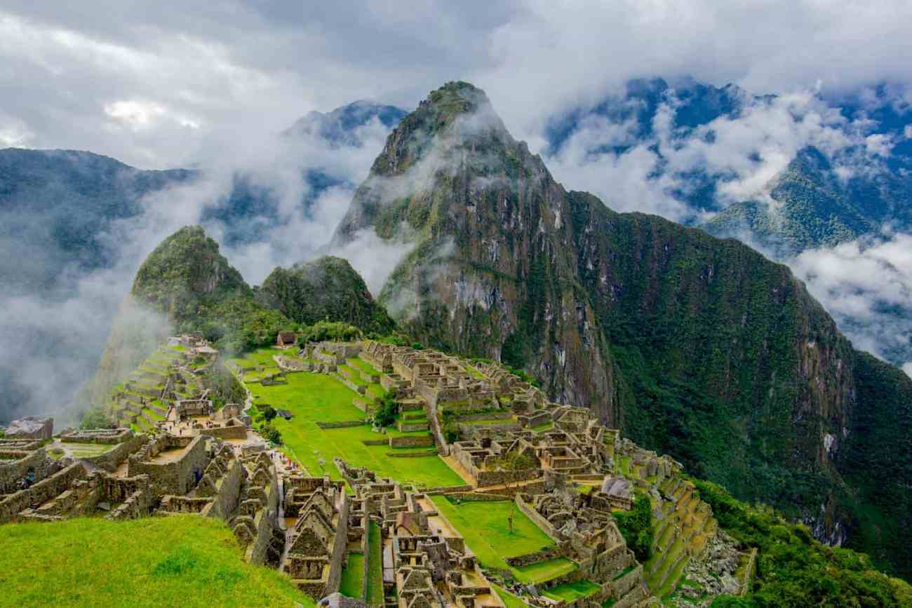 Stunning aerial view of Machu Picchu ruins surrounded by lush mountains and mist.