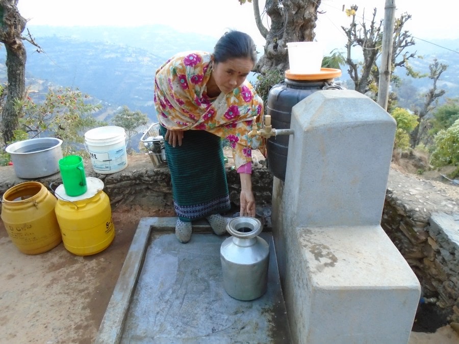 Maya Reshmi collecting water from the new tap stand outside her home